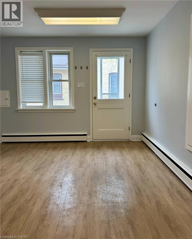 A room with a door, window, and wooden floor.