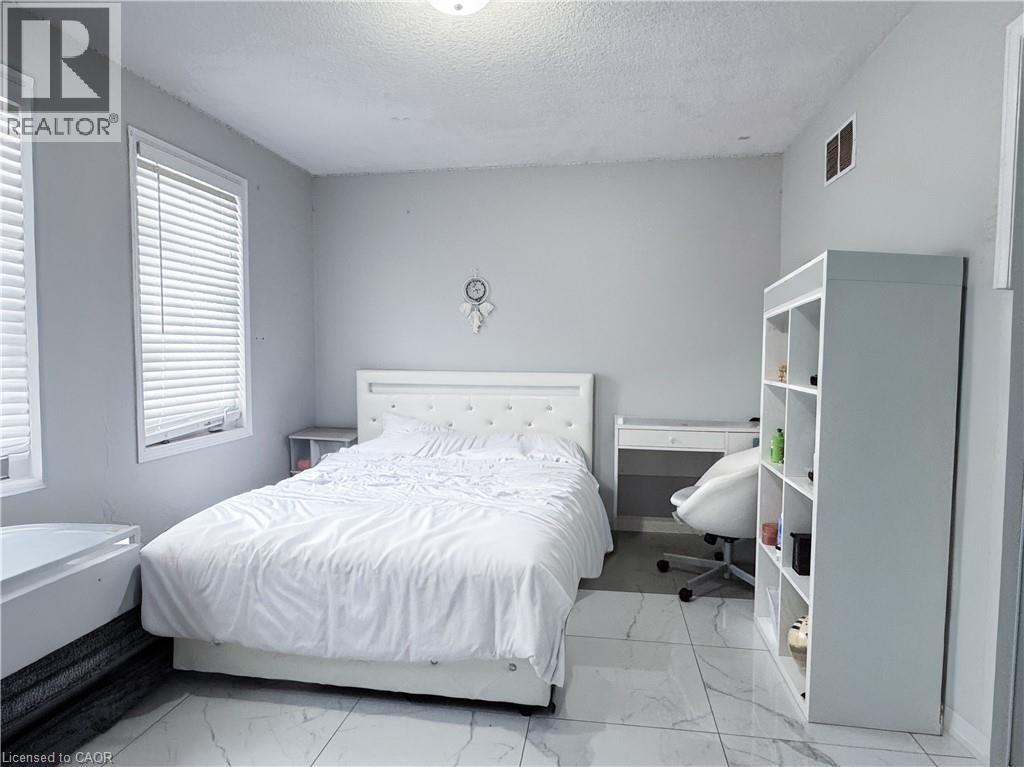A white bedroom with a large bed and a white bathtub.