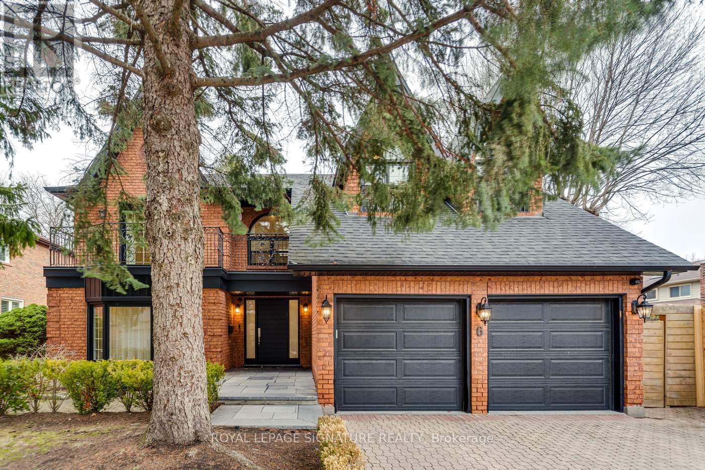 A house with a black front door and a tree in front.