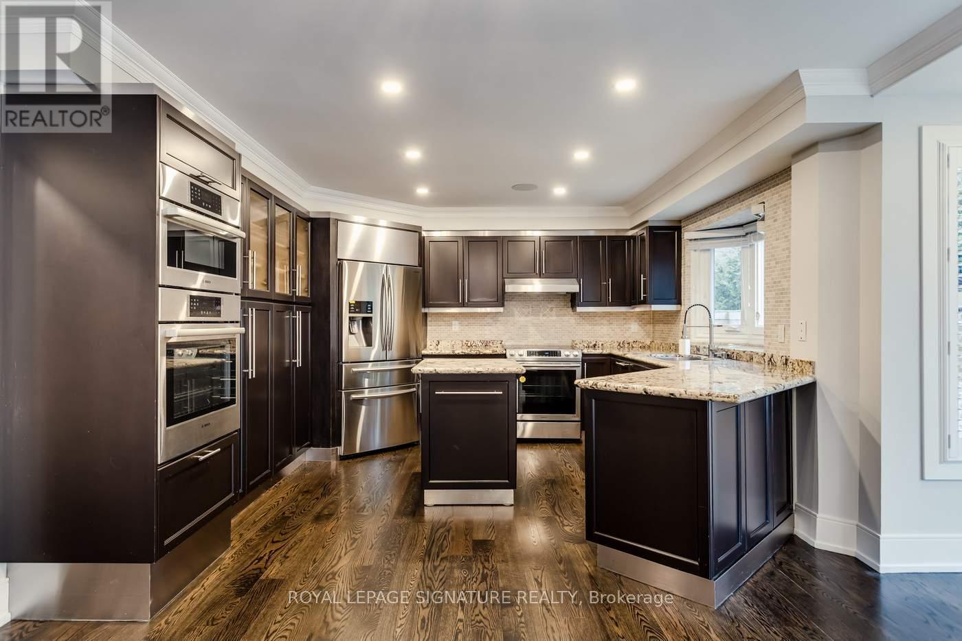A modern kitchen with dark wood cabinets and stainless steel appliances.