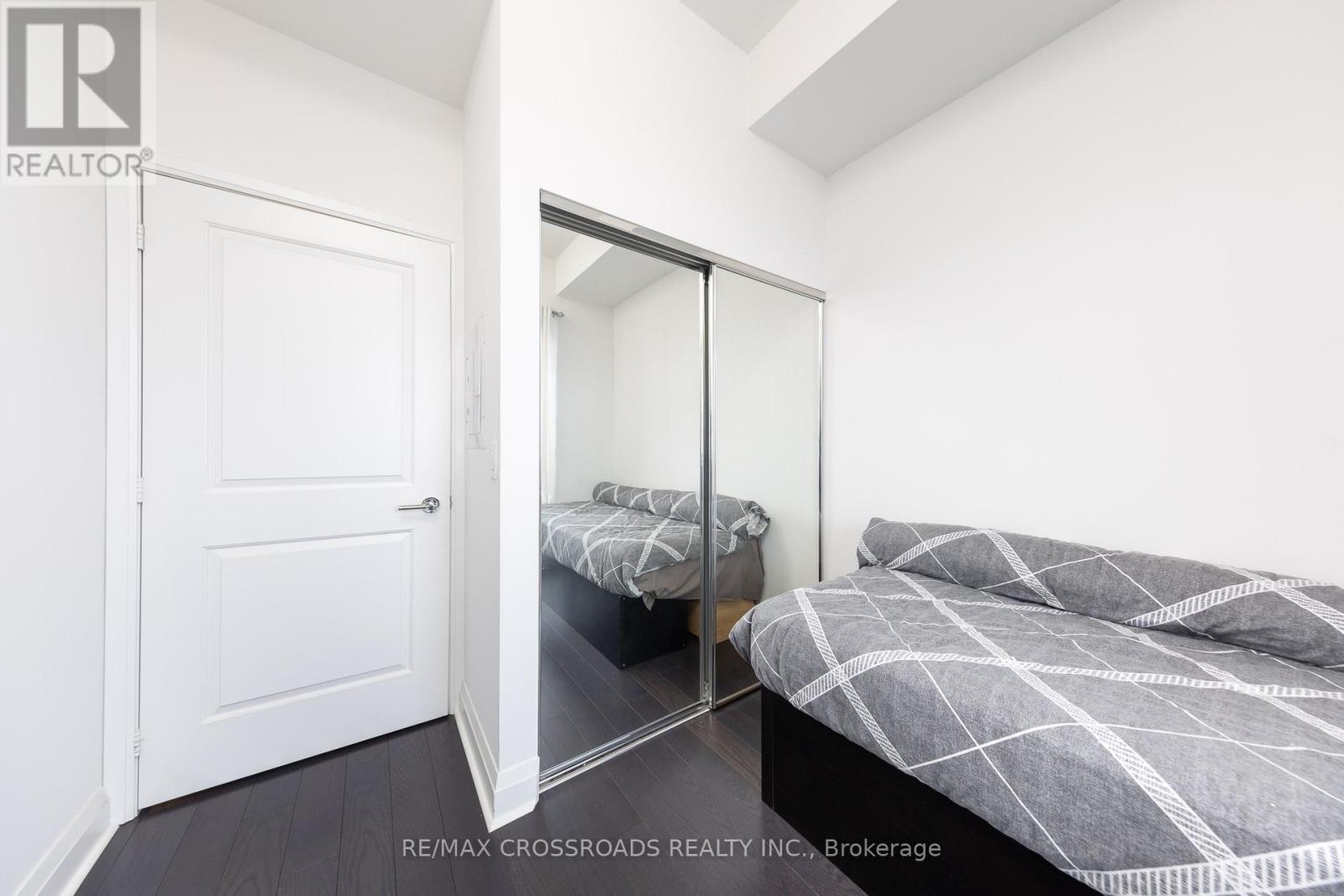 A bedroom with a bed and a mirrored closet door.