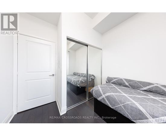 A bedroom with a bed and a mirrored closet door.