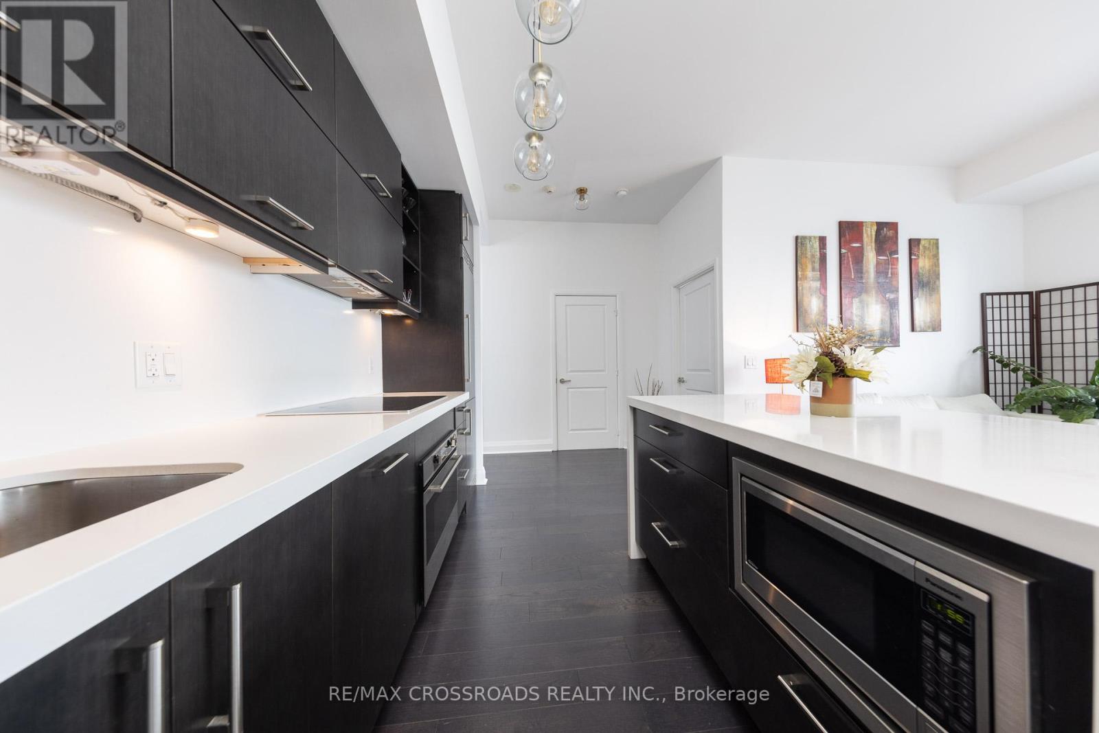 A modern kitchen with black cabinets and stainless steel appliances.