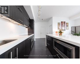 A modern kitchen with black cabinets and stainless steel appliances.