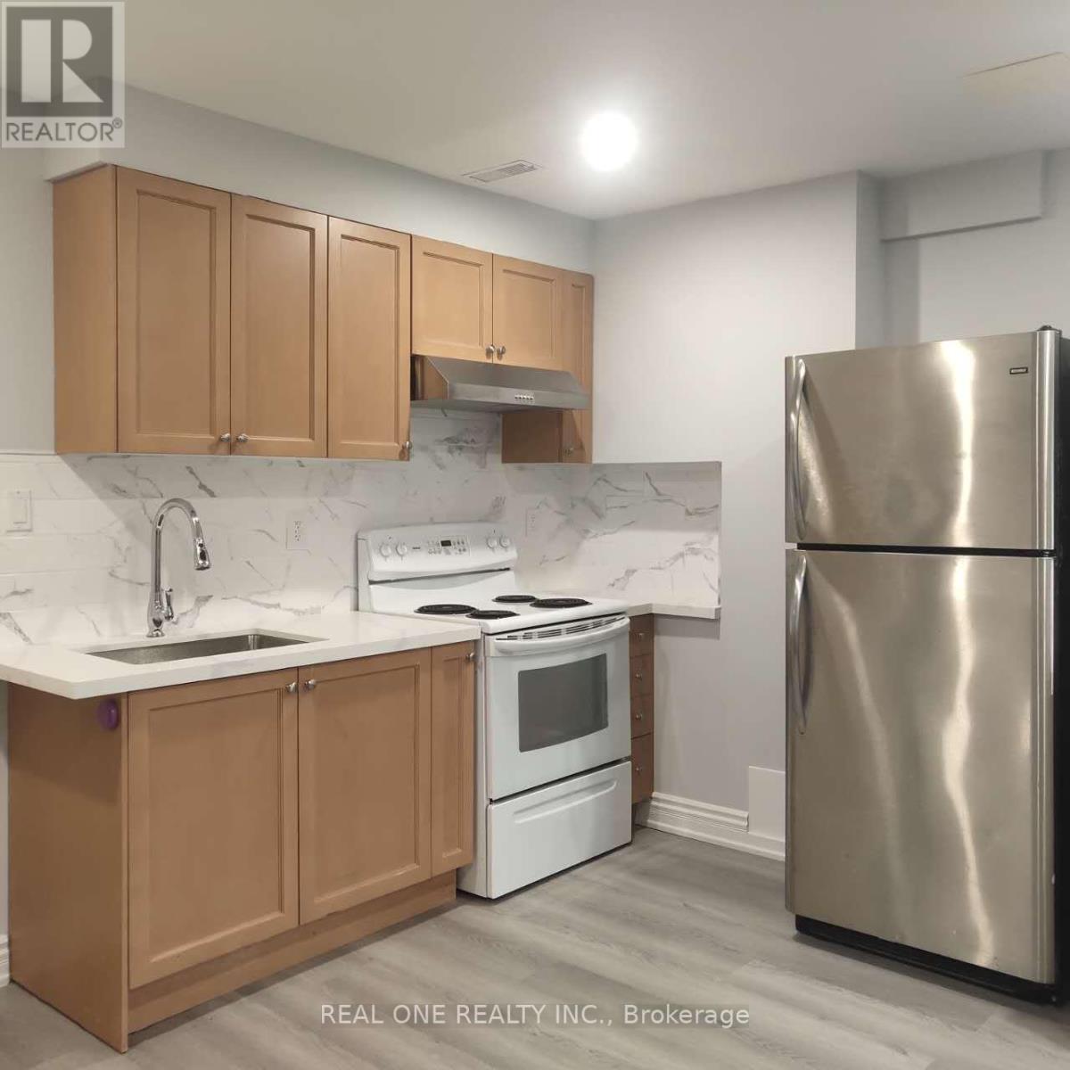 A kitchen with a stainless steel refrigerator, white oven, and wooden cabinets.