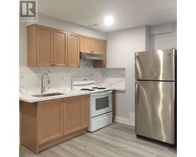 A kitchen with a stainless steel refrigerator, white oven, and wooden cabinets.