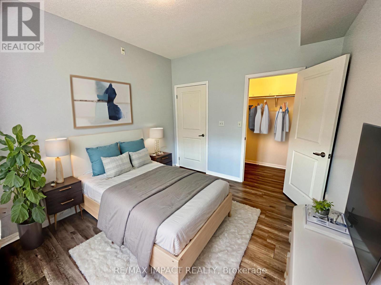 A bedroom with a bed, a plant, and a painting on the wall.