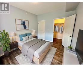 A bedroom with a bed, a plant, and a painting on the wall.