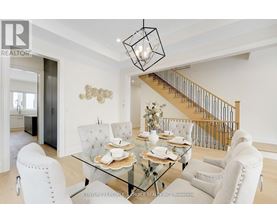 A dining room with a glass table and white chairs.
