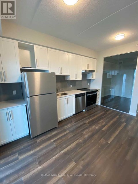 A kitchen with white cabinets and a stainless steel refrigerator.