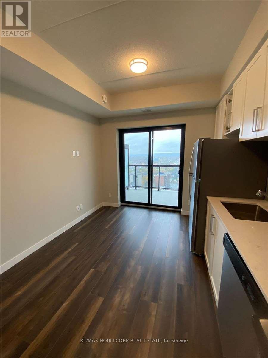 A kitchen with dark wood floors and white walls.