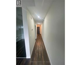 A hallway with wood floors and white walls.