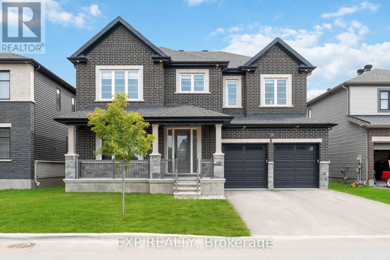 A large house with a grey front yard and a tree.