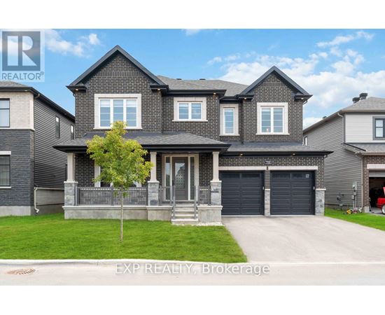 A large house with a grey front yard and a tree.