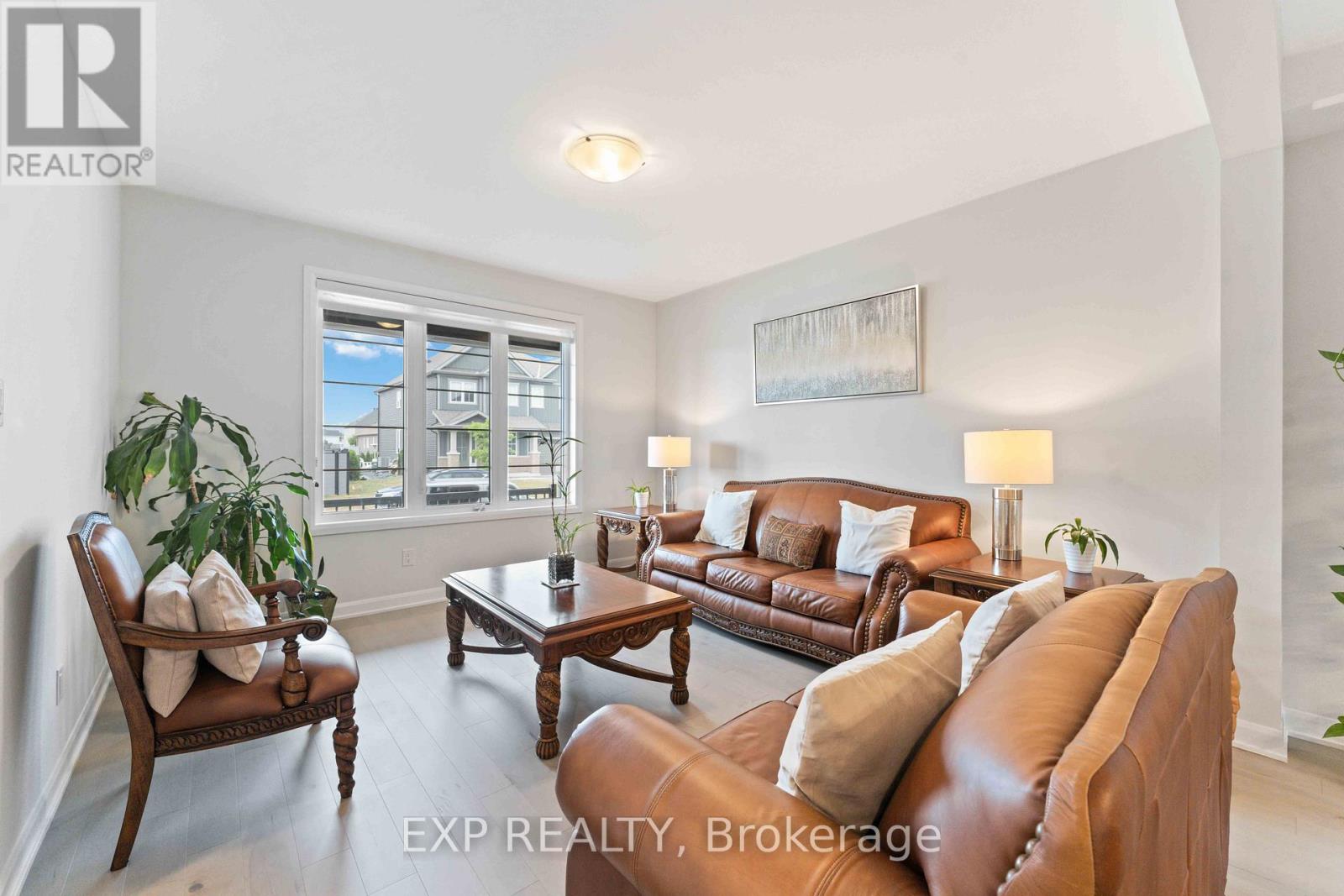 A living room with a brown leather couch and a wooden chair.