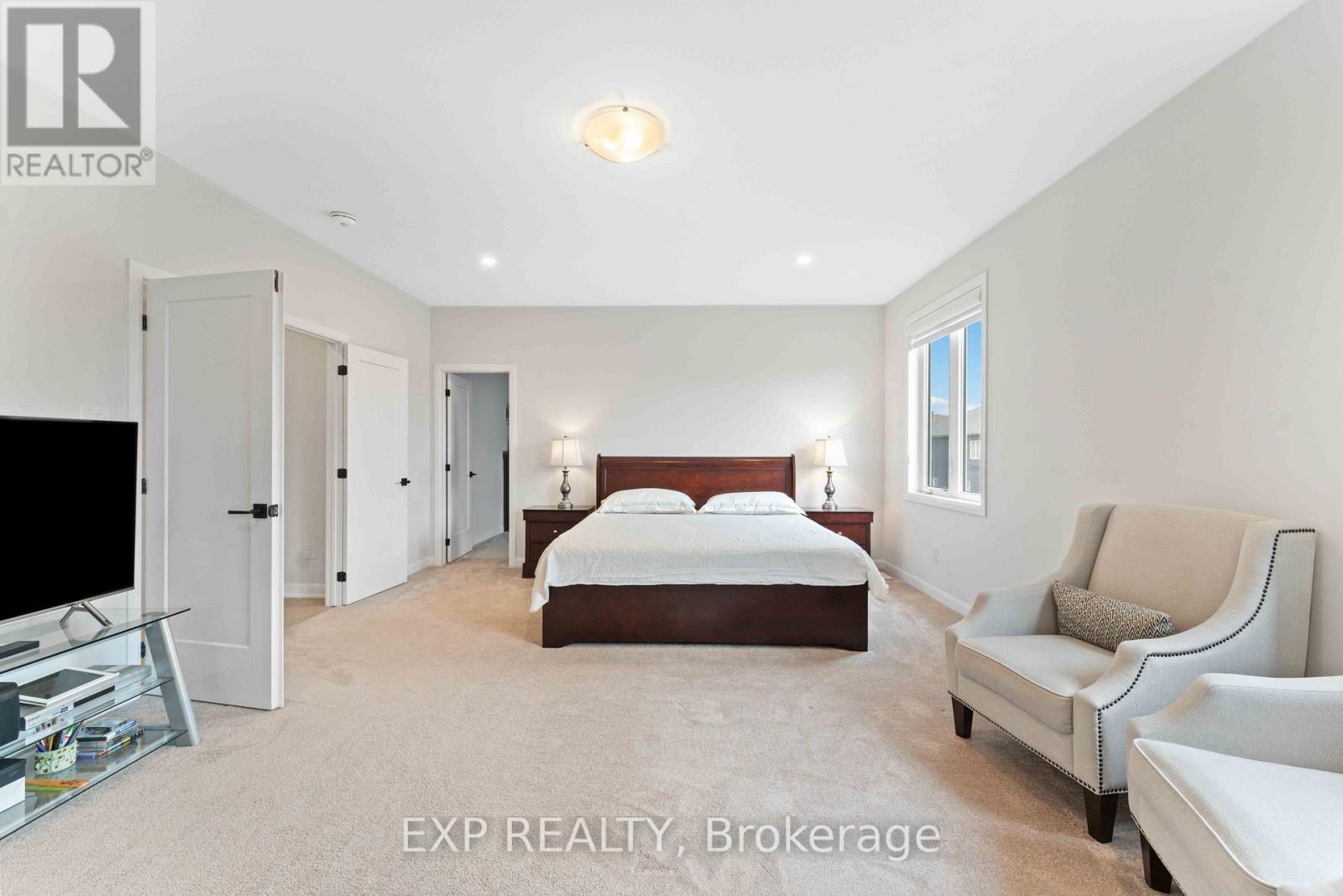 A bedroom with a bed, a chair, and a television.