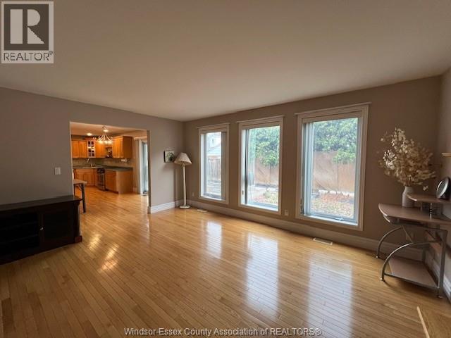A spacious room with wooden flooring and large windows.