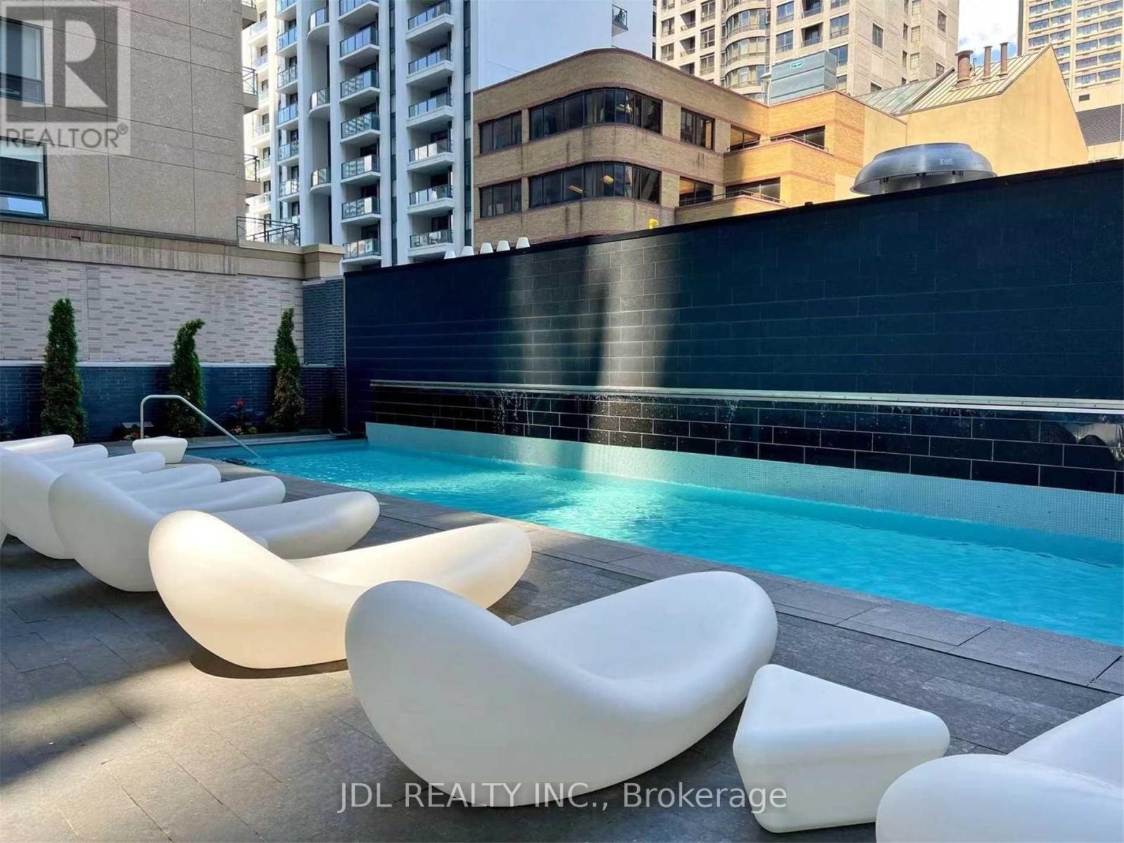 A pool surrounded by white lounge chairs.