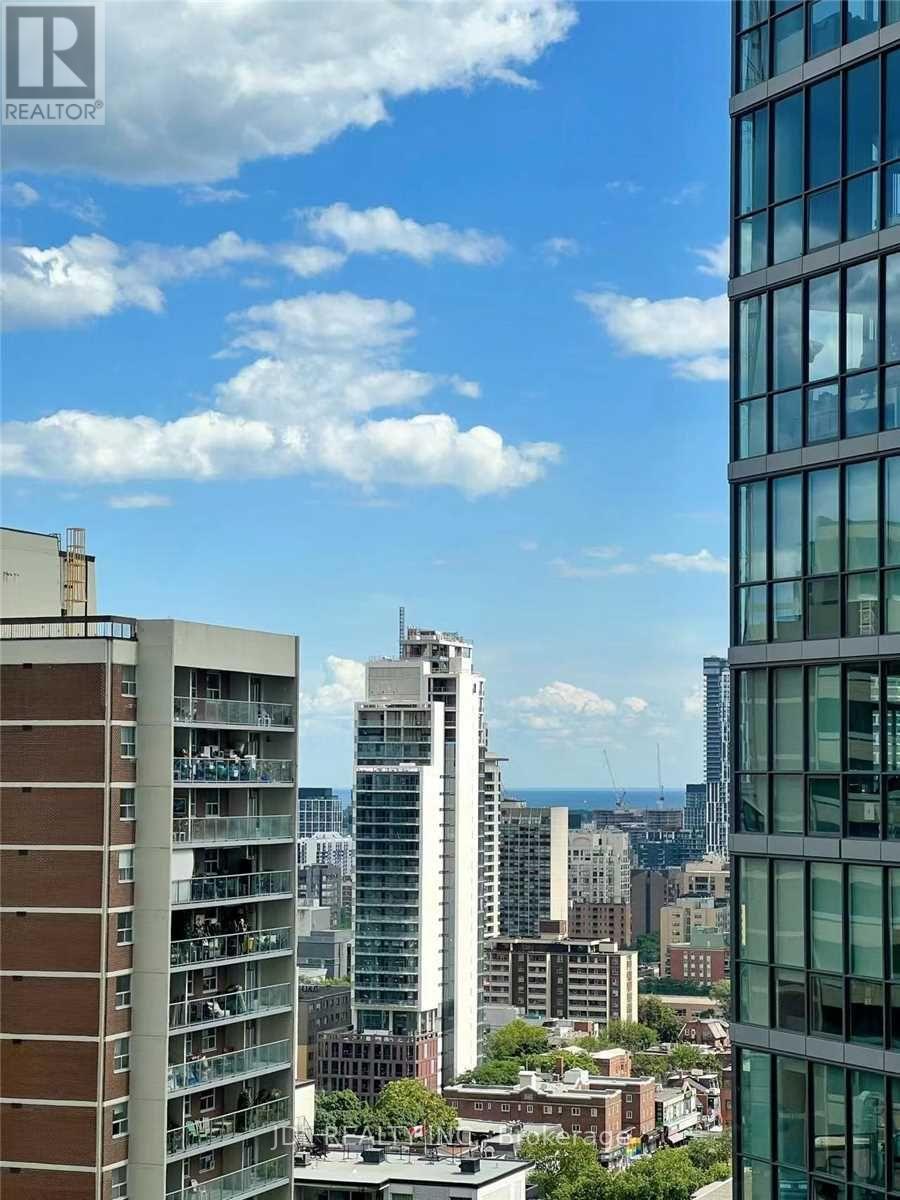 A cityscape with buildings of various heights and architectural styles under a blue sky with clouds.