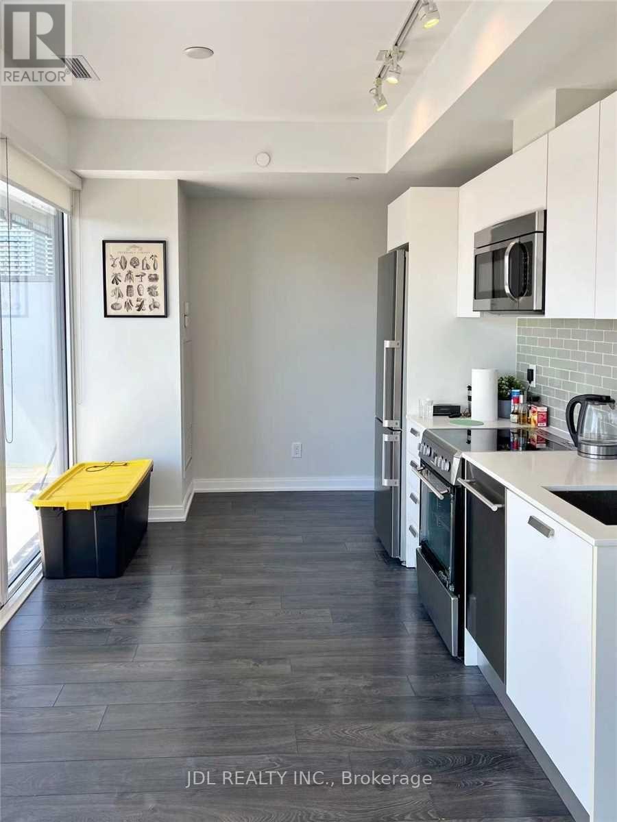 A kitchen with white cabinets and a black fridge.