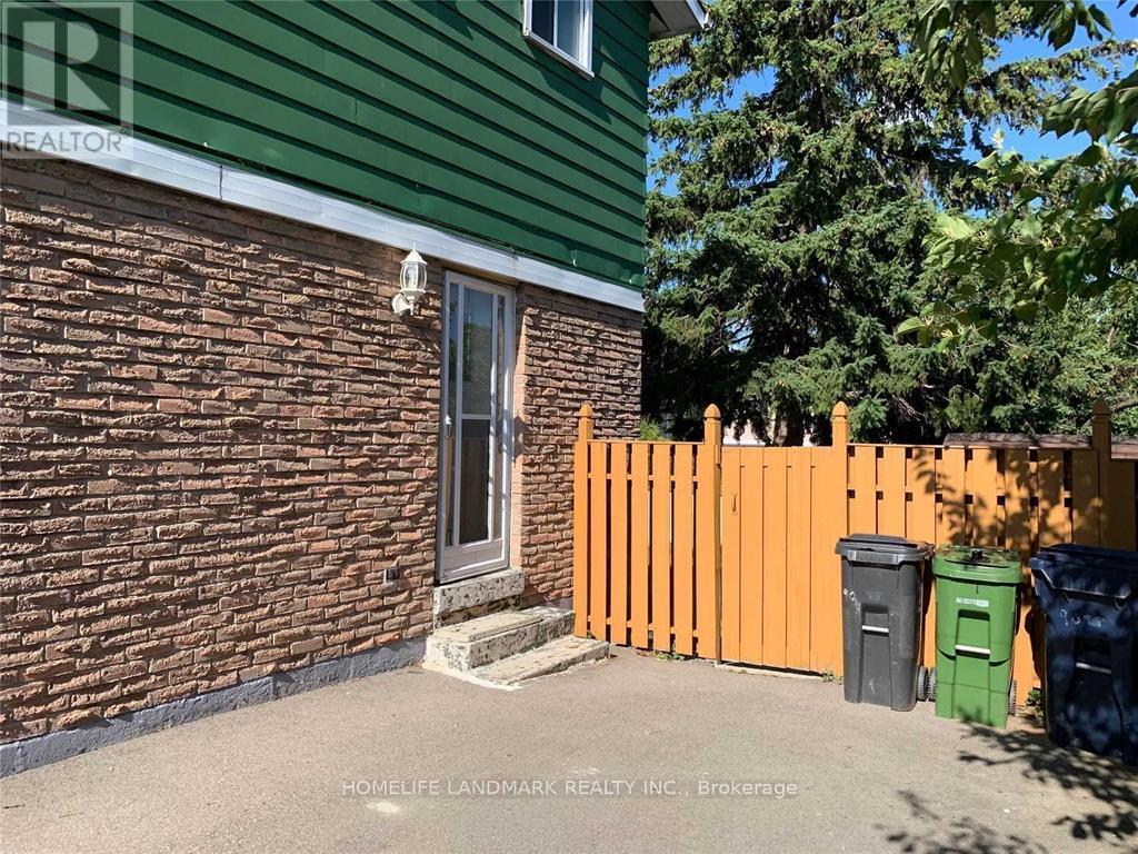 A green house with a brown brick wall and a grey door.