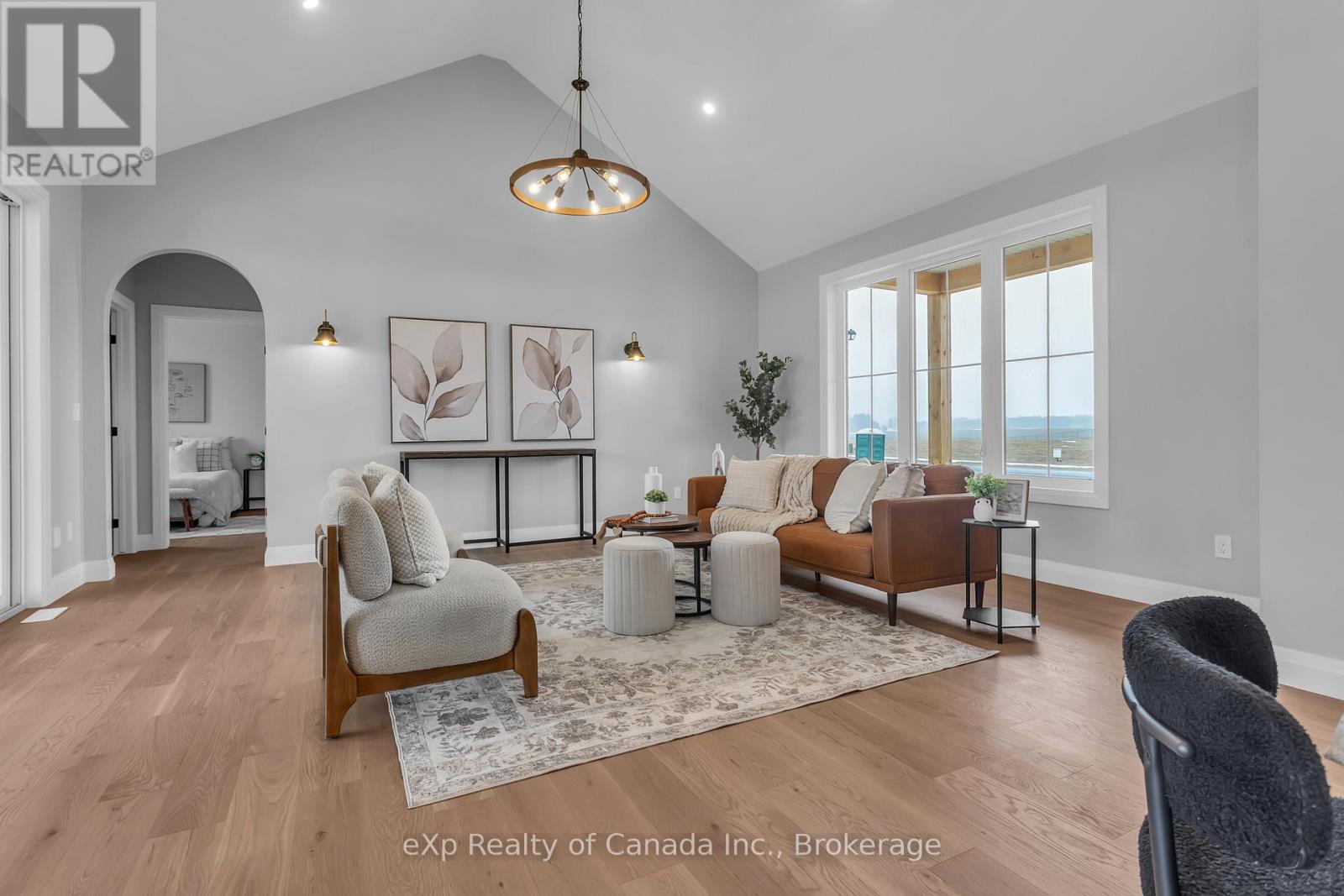 A living room with a grey sofa, a white armchair, and a wooden floor.