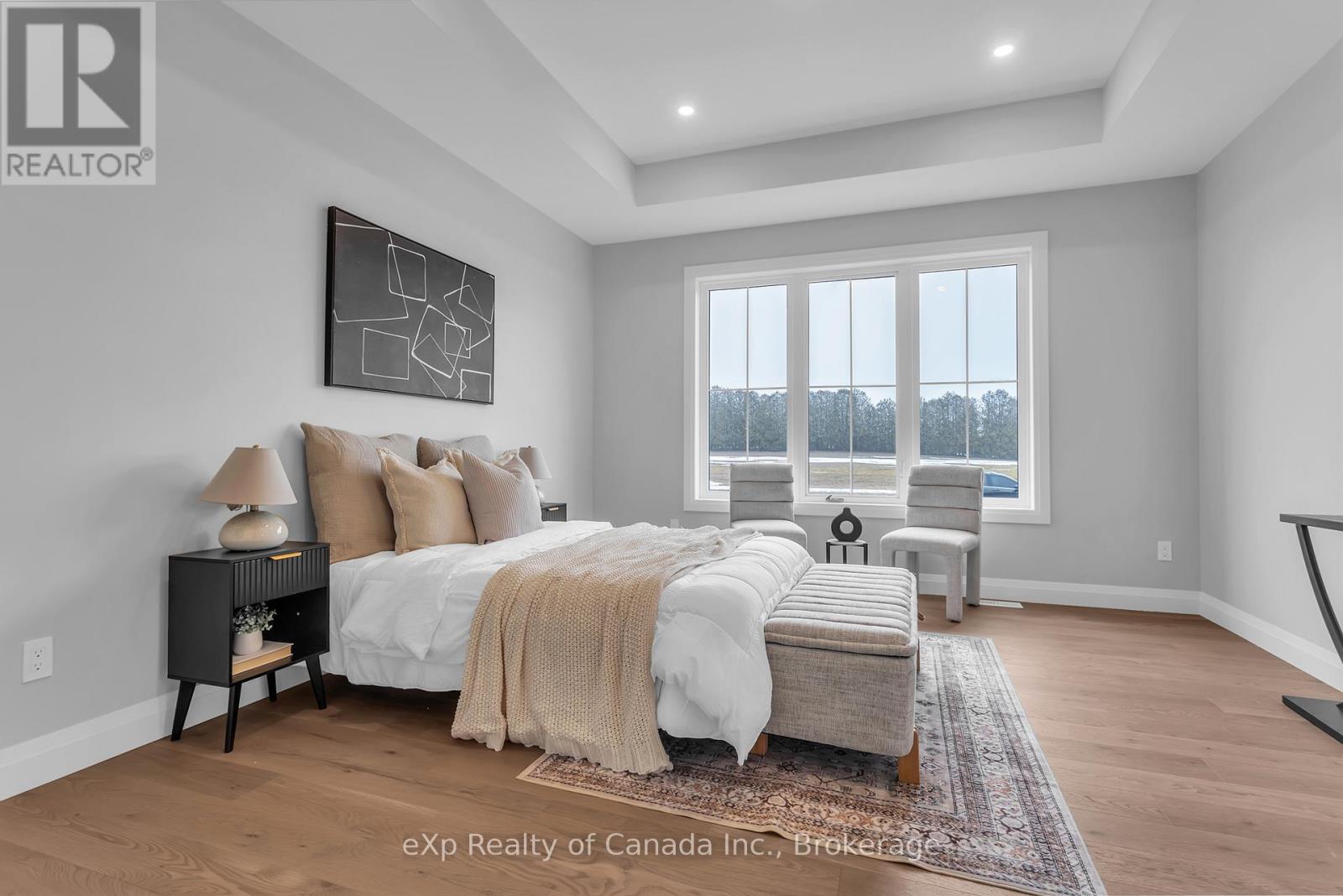 A bedroom with a large bed and a window overlooking trees.