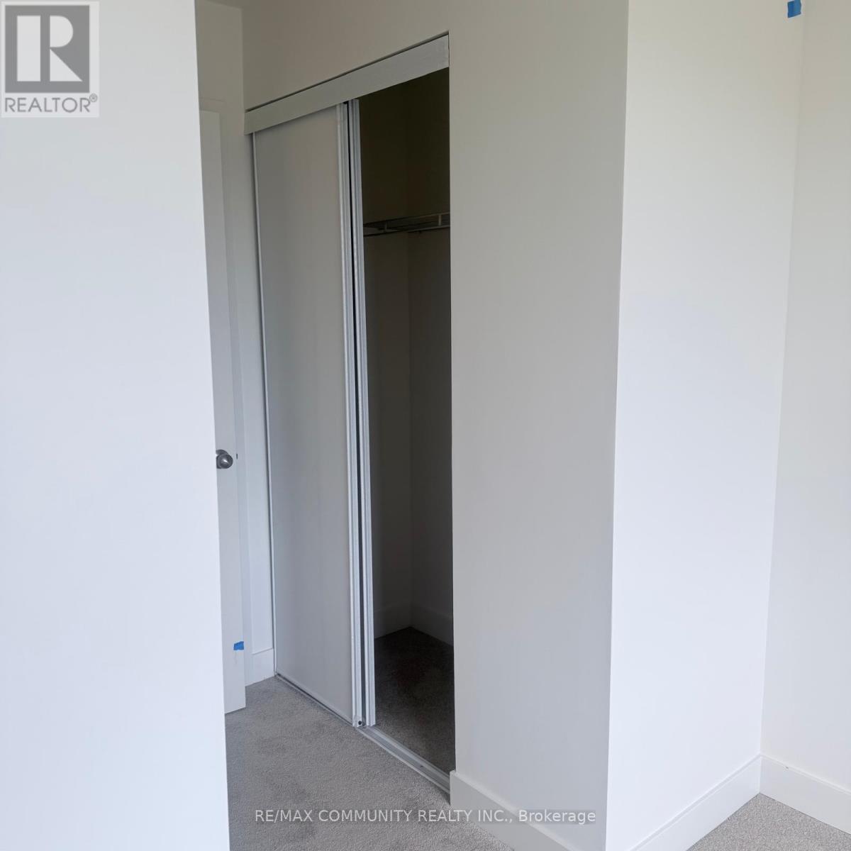 A white door with a glass panel is open in a white room.