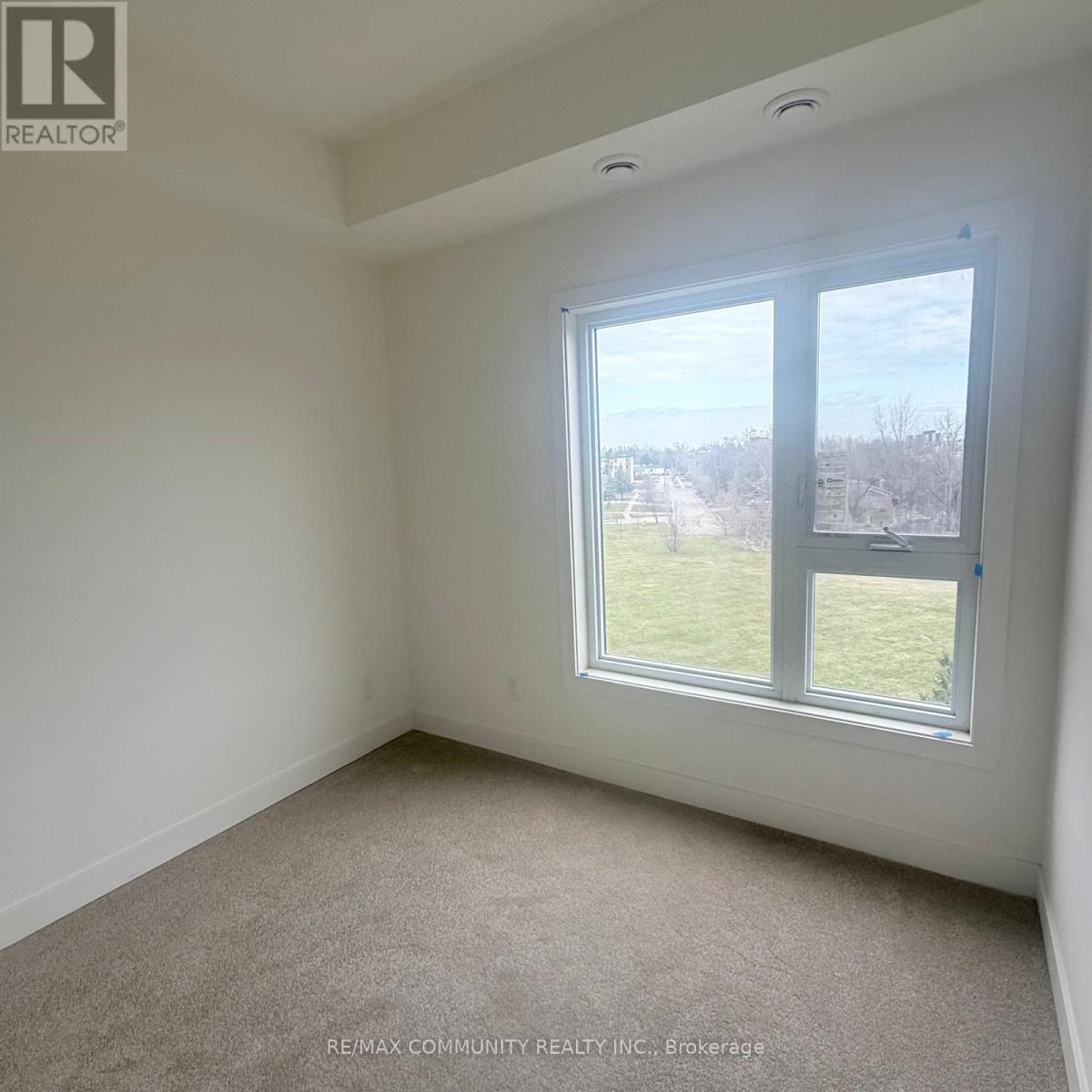 A room with a large window and a view of a grassy area outside.