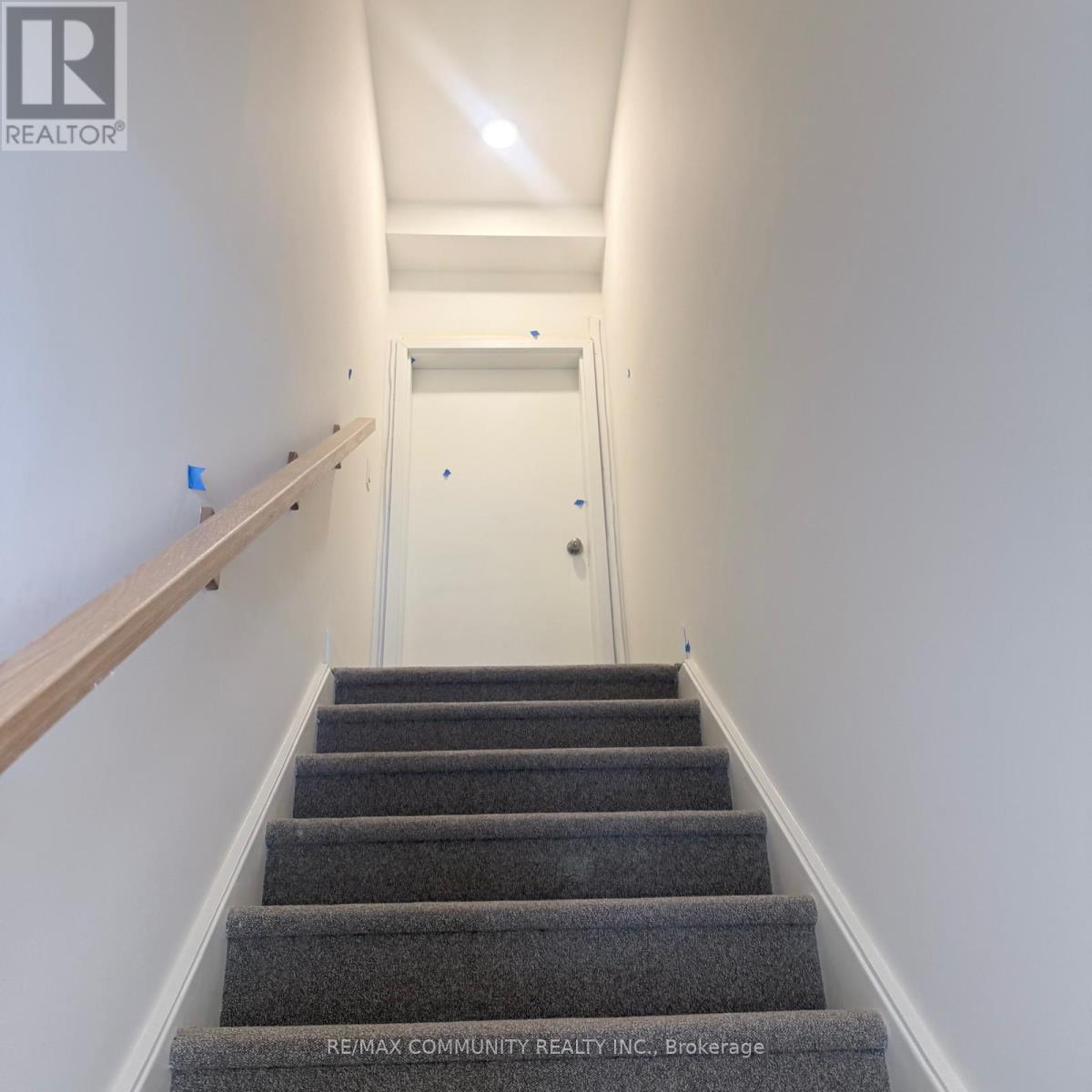 A hallway with a staircase and a door at the end.