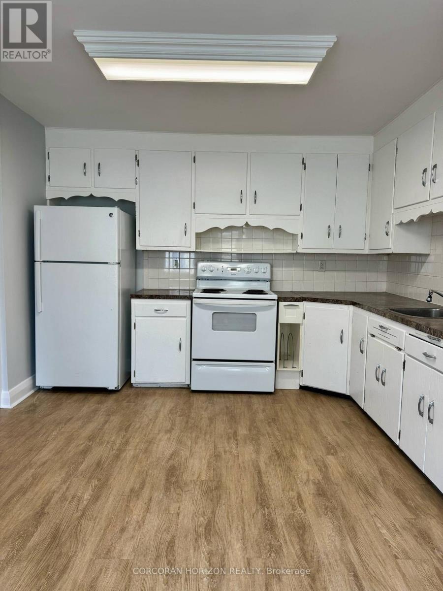 A white kitchen with wooden floors and white appliances.