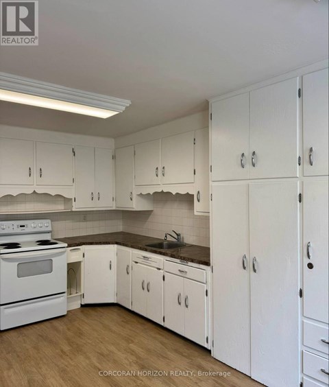 A kitchen with white cabinets and a stove top oven.