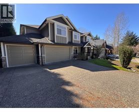 A large house with a grey garage door is for sale.