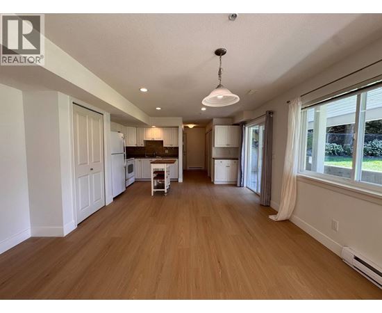 A spacious room with wooden flooring and a white ceiling.