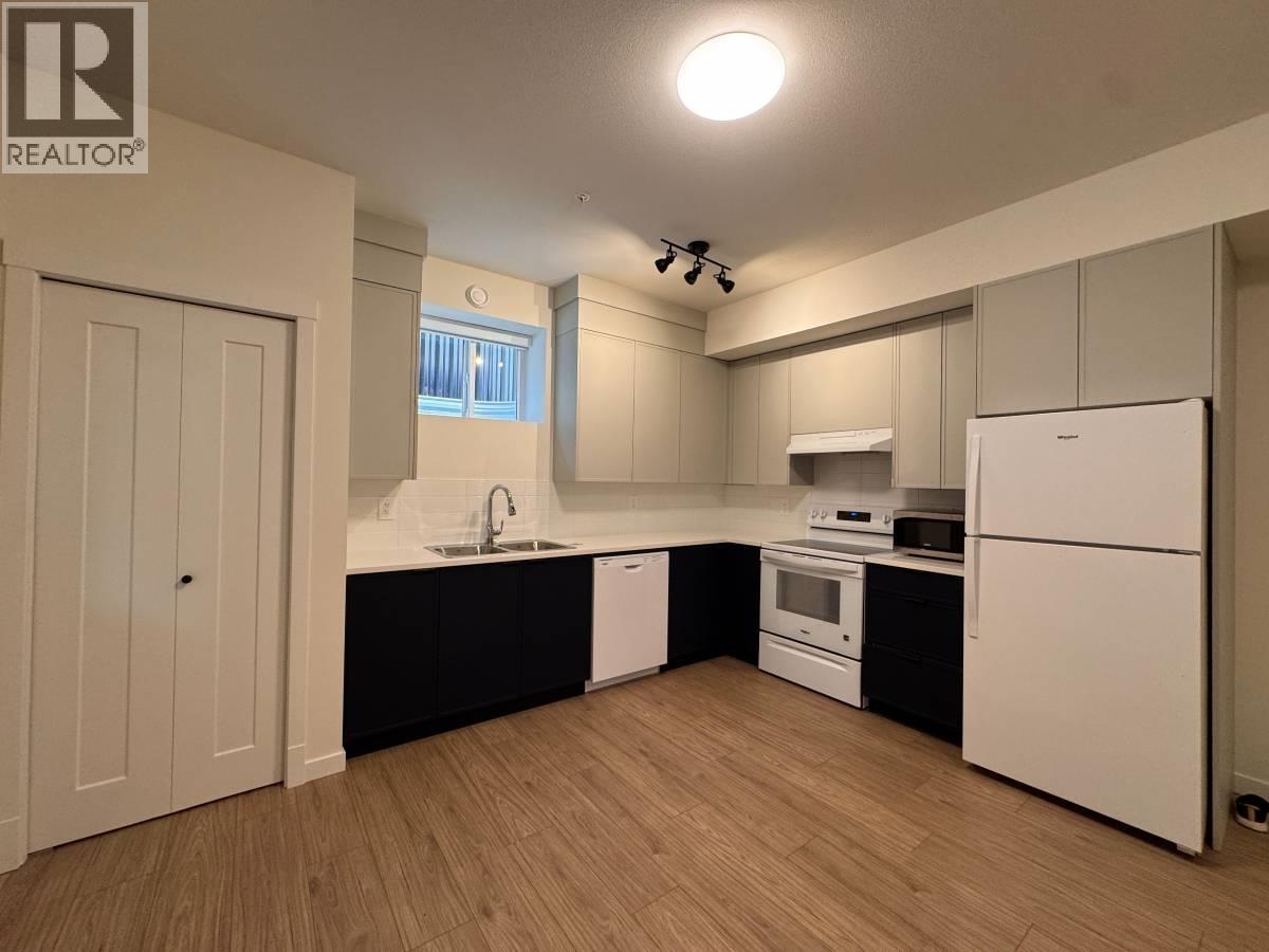 A kitchen with white appliances and wooden floors.
