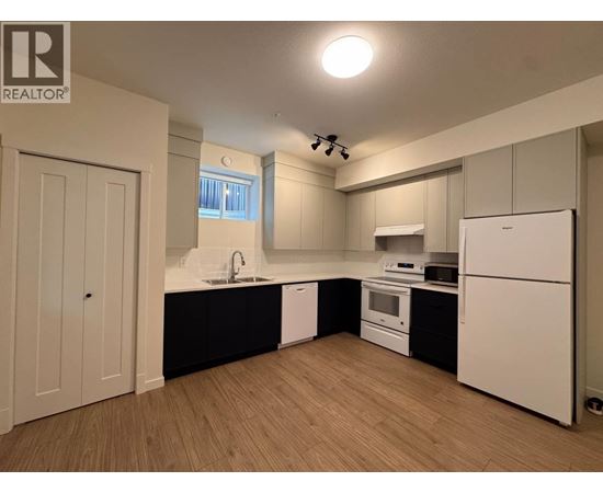 A kitchen with white appliances and wooden floors.