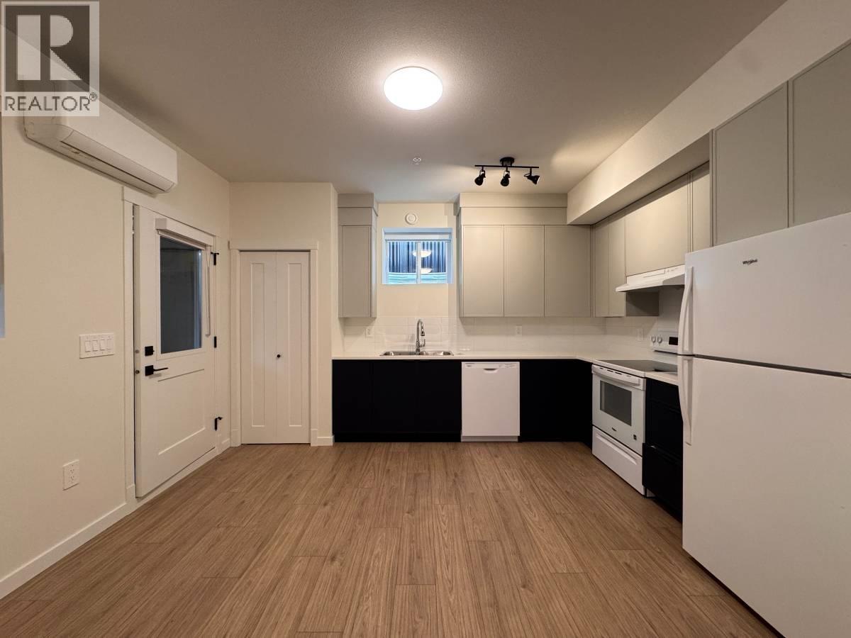 A kitchen with white appliances and wooden floors.