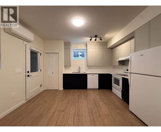 A kitchen with white appliances and wooden floors.