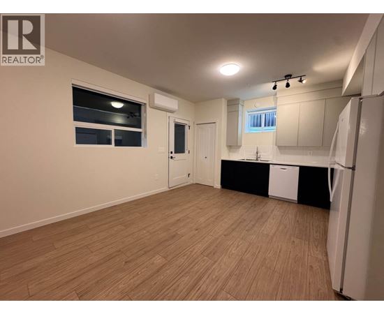 A well-lit, empty room with wooden flooring and white walls.