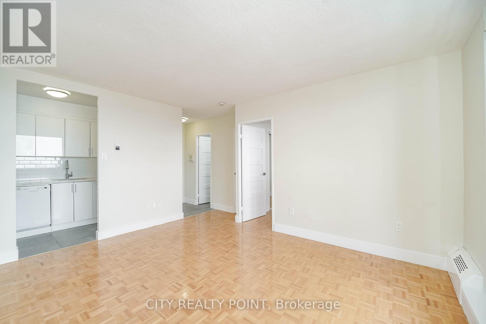 A spacious room with wooden flooring and white walls.
