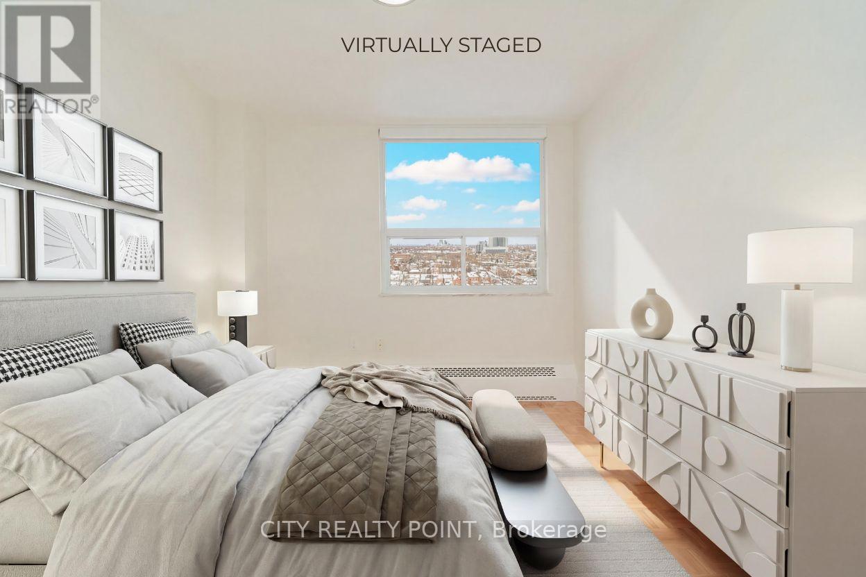 A bedroom with a large bed and a cityscape view through the window.
