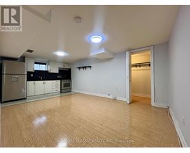 A well-lit, empty room with wooden flooring and white walls.