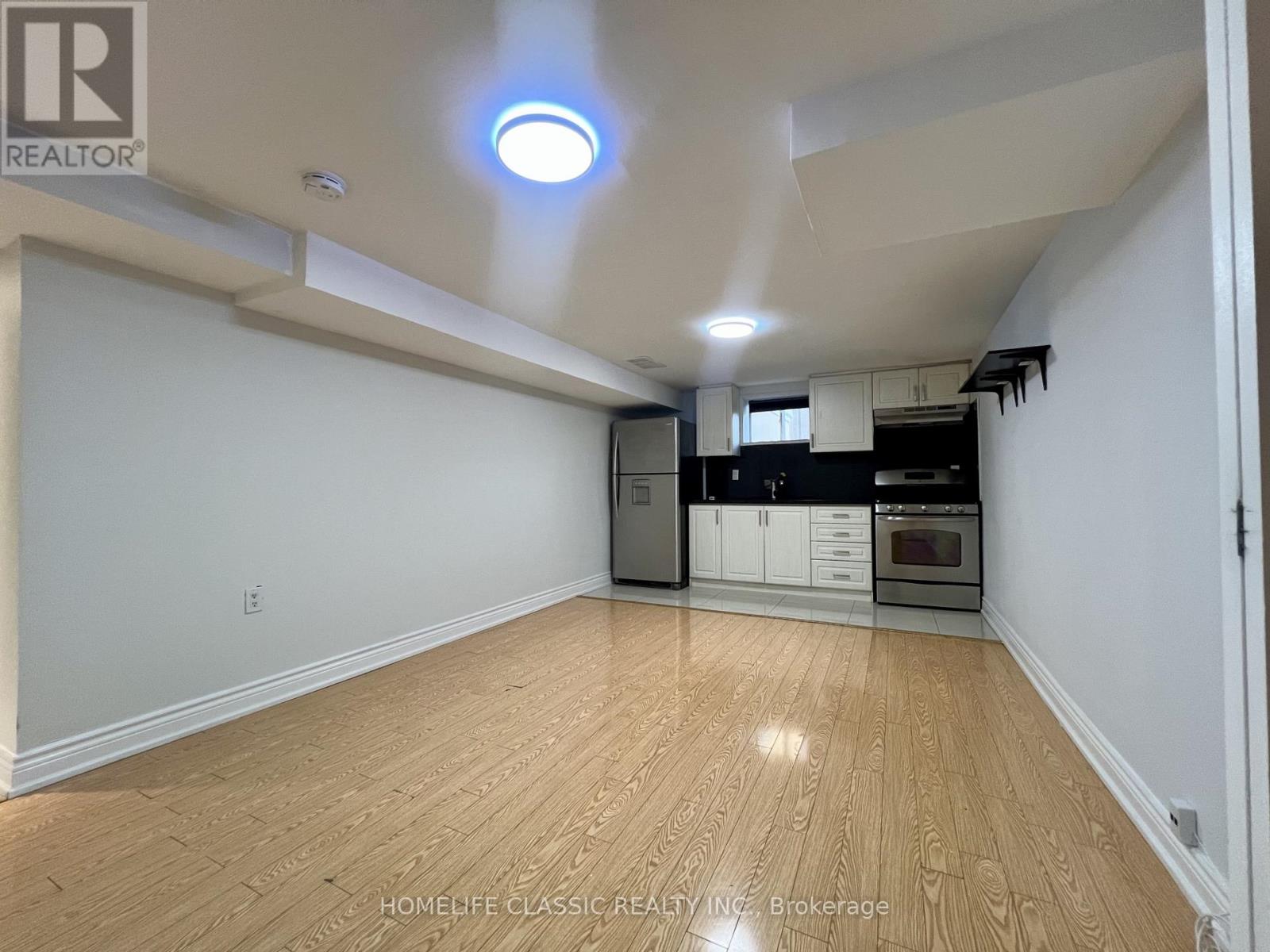 A spacious kitchen with wooden flooring and white walls.