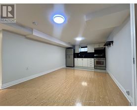 A spacious kitchen with wooden flooring and white walls.