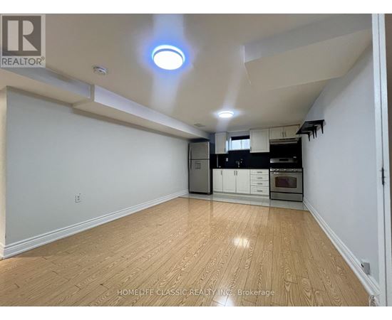 A spacious kitchen with wooden flooring and white walls.