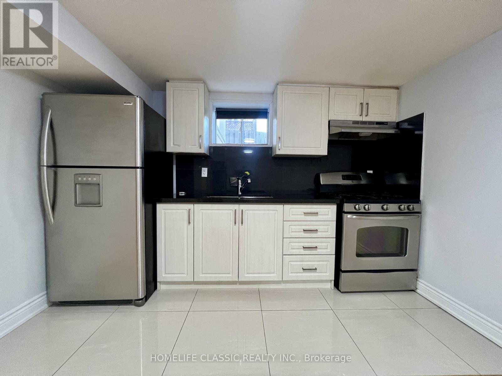 A kitchen with white cabinets and a stainless steel refrigerator.