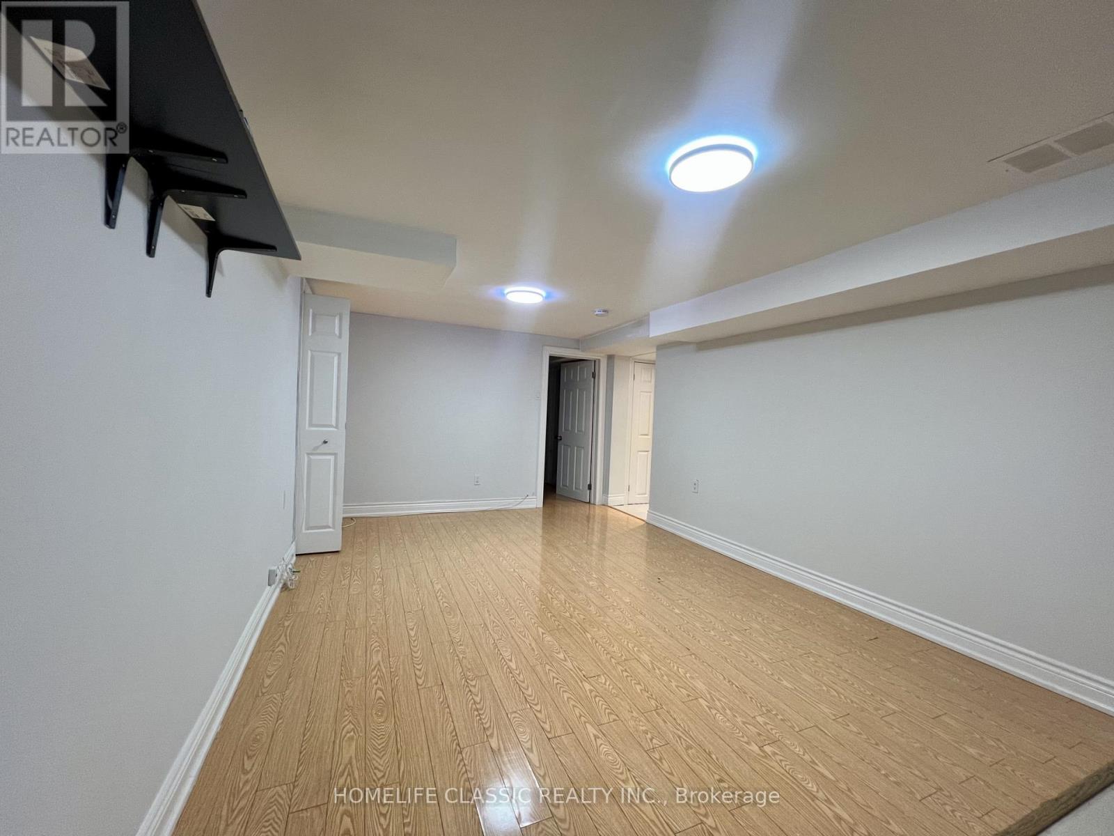 A room with wooden flooring and white walls, with a light on the ceiling.