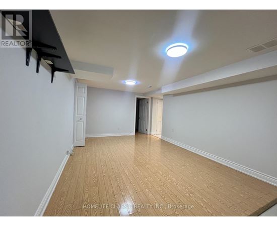A room with wooden flooring and white walls, with a light on the ceiling.