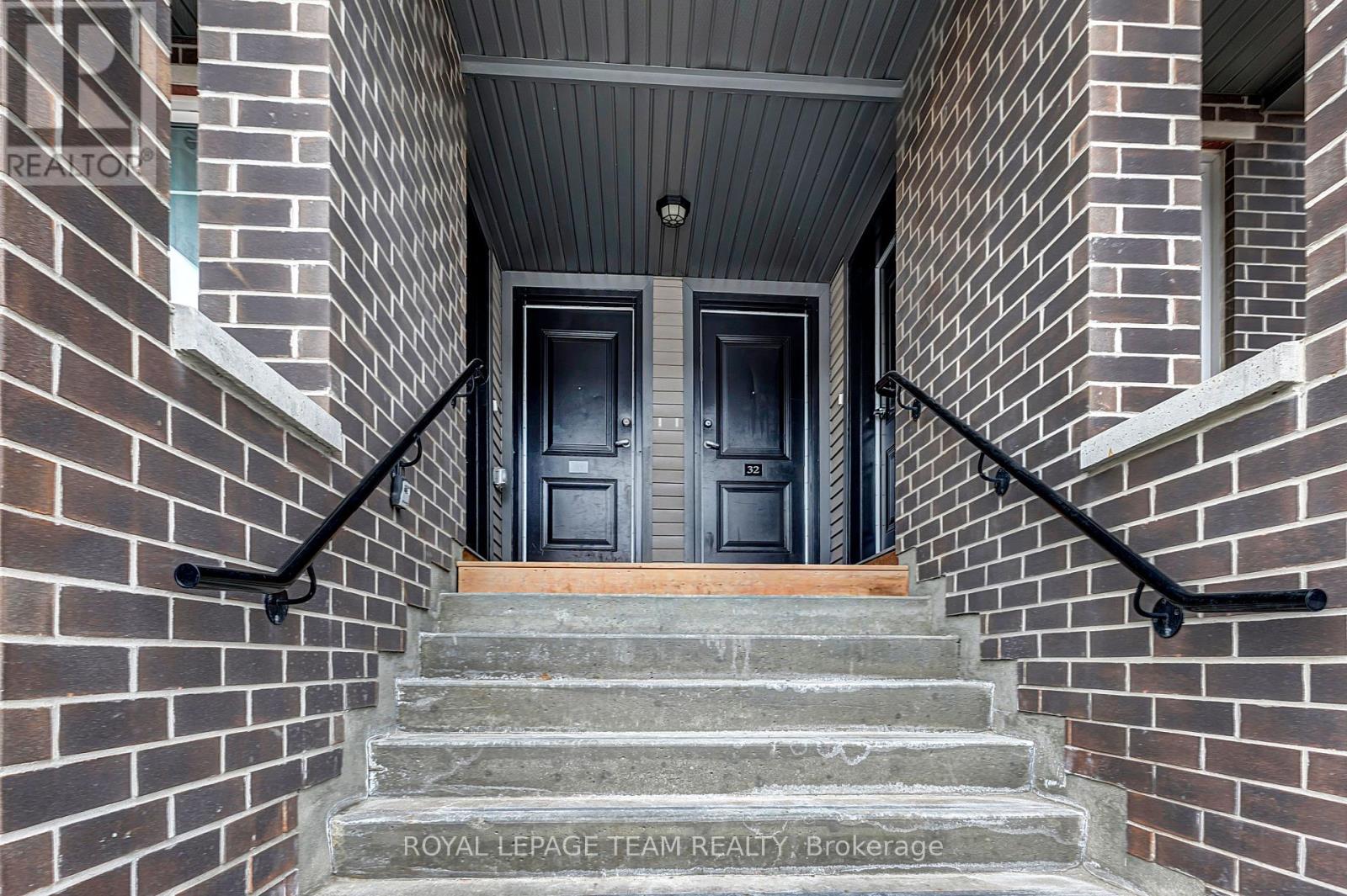 A set of stairs leading to a black door with a wooden step.