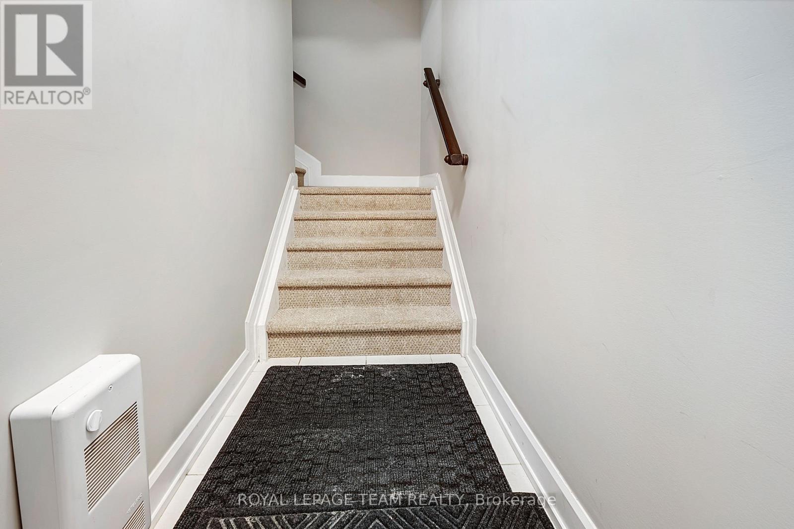 A staircase with a carpeted runner and beige stairs.